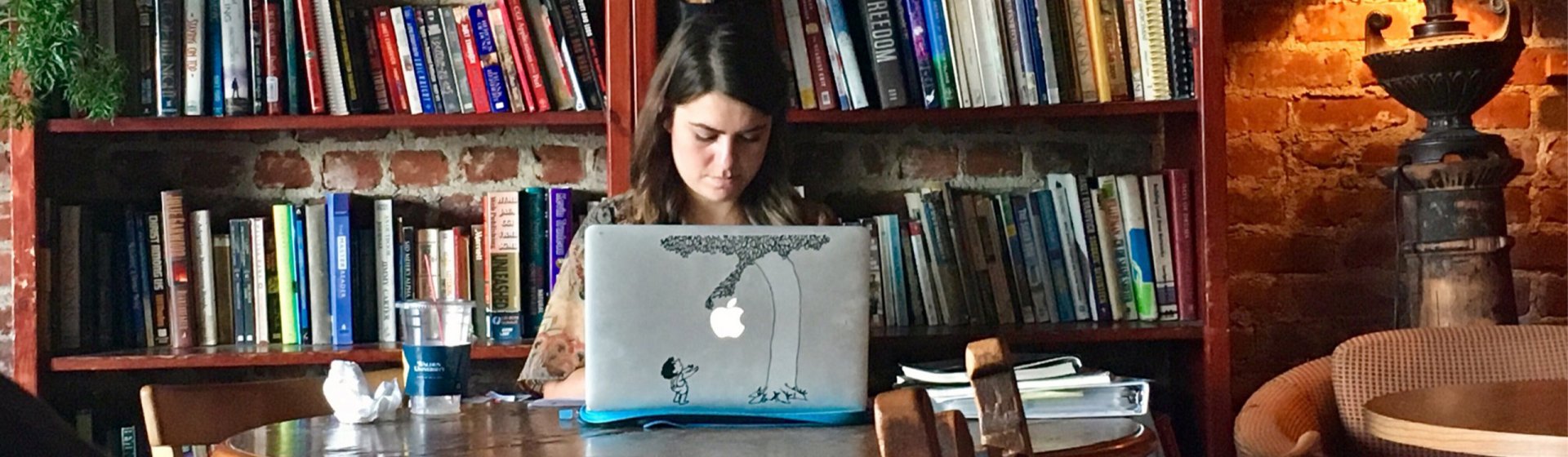 Frau mit Laptop vor Bücherregal